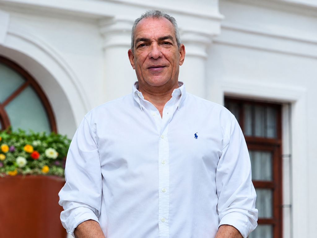 Persona con camisa blanca frente a un edificio institucional.